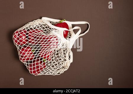 Peperone rosso in mesh bianca, borsa riutilizzabile, vista dall'alto. Concetto di shopping ecologico. Mangiare sano. Foto Stock