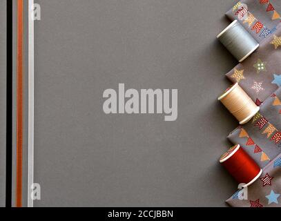 Una vista ad occhio di uccello degli accessori da cucire con cotone, nastri di seta e materiale su sfondo grigio. Foto Stock