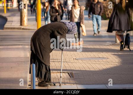 Persone che si avvicinano ad una vecchia donna anziana che tiene un bastone e. Pregando di denaro per le strade di Sofia Bulgaria Foto Stock