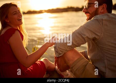 La giovane coppia ha un momento meraviglioso godendosi il tramonto sul lago Foto Stock