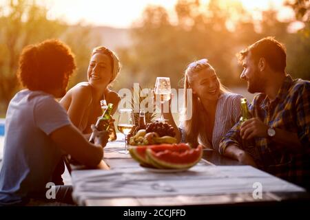 I giovani amici si divertono all'aperto, parlano e si divertono a ridere la sera. Foto Stock