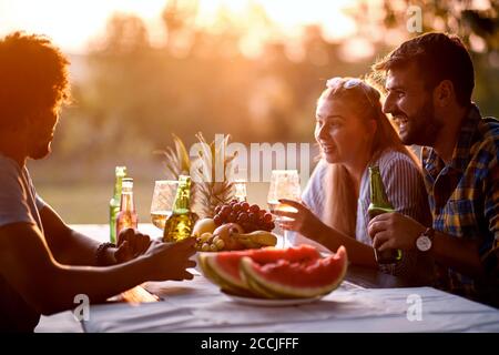 Sorridi gli amici che si divertono la sera e bevono insieme. Foto Stock