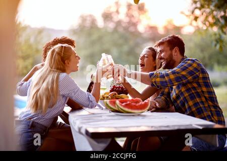 I giovani si divertono all'aperto, parlano e ridono godendosi l'amicizia. Foto Stock