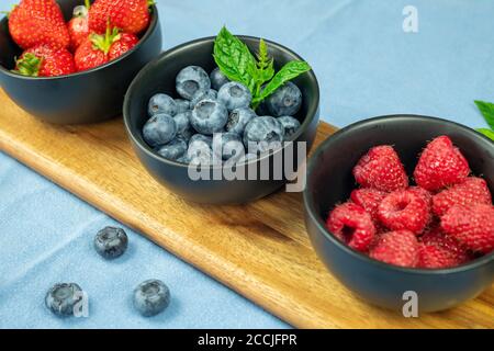 Selezione di fragole di frutta mirtilli e lamponi su un cibo plater e ciotola che mostrano una sana scelta di cibo Foto Stock