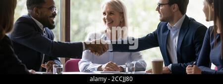 Felice diversi partner di affari maschili scuotendo le mani Foto Stock