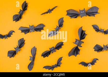 Molti pipistrelli fatti di carta su uno sfondo arancione. Disposizione piatta. Il concetto di Halloween, e decorazioni per le vacanze. Foto Stock