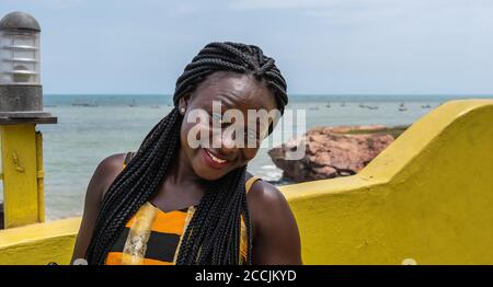 Donna felice africana vestita in abiti colorati che si abbinano a. Colore di una scala sulla costa di Accra in Ghana Foto Stock