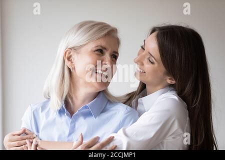 Felice figlia cresciuta abbracciando la madre con amore Foto Stock