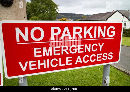 segnale rosso di accesso per veicoli di emergenza senza parcheggio all'esterno della stazione dei vigili del fuoco nel distretto dei laghi di coniston, cumbria, inghilterra, regno unito Foto Stock