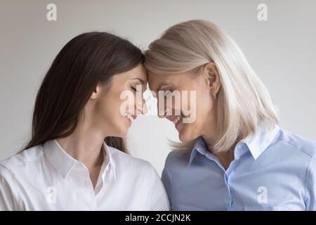 Madre e figlia cresciuta in piedi faccia a faccia a contatto con le teste Foto Stock