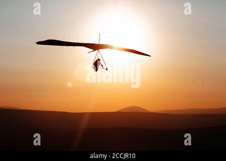 Volo con deltaplano in cielo al tramonto sulle colline galileiane, Mevo Hama, Israele Foto Stock