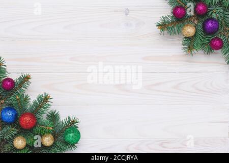 Motivo ornamenti natalizi, carta Capodanno con ramo in abete e palle lucenti, modello festivo su sfondo bianco in legno. Mockup con posto per il testo. Foto Stock