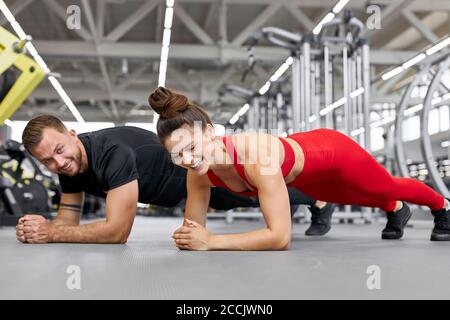 giovane uomo caucasico e atleti di donna che fanno push-up durante la croce allenamento in palestra Foto Stock