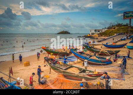 Vung Tau, Vietnam - 22 ago 2020: Vista dei pescatori locali che spingono le tradizionali barche di legno blu dal mare alla riva in modo tradizionale, raccolgono il fishe Foto Stock