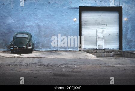 Merida, Yucatan, Messico - 26 gennaio 2019: Verde scuro vintage Volkswagen Beetle parcheggio in un edificio abbandonato con garage cancello Foto Stock