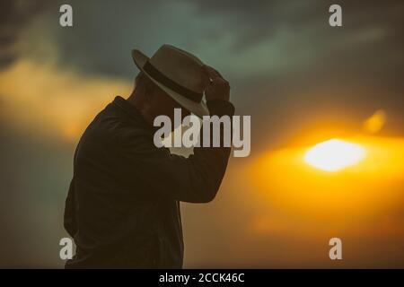 Uomo anziano che inzina di fronte al sole che tramonta Foto Stock