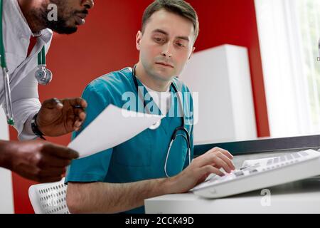 assistente africano mostra documento al medico veterinario, check-up di animali in clinica, parlare Foto Stock