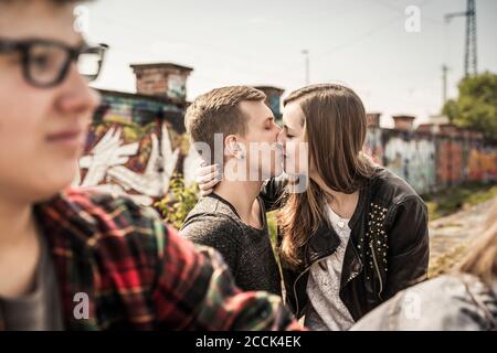 Una coppia adolescente che si baciano in una vecchia zona industriale Foto Stock