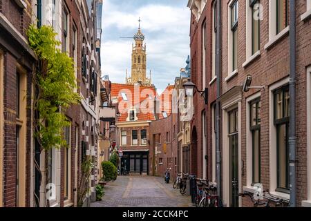 Olanda, Olanda del Nord, Haarlem, vicolo vuoto tra vecchie case storiche con la torre di Bakenesserkerk sullo sfondo Foto Stock