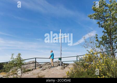 Germania, Renania Settentrionale-Vestfalia, Monschau, uomo ammirando le viste dalla croce in piedi sulla cima di Ehrensteinley Foto Stock