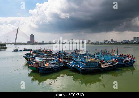 Vietnam, da Nang, nuvole tempesta su vecchie barche da pesca ormeggiate nel porto della città Foto Stock