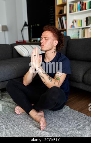 L'uomo pregava mentre era seduto a terra a casa Foto Stock