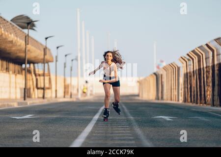 Giovane donna pattinaggio sul Boardwalk presso la costa Foto Stock