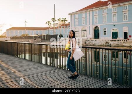 Giovane donna che cammina da ponte ringhiera all'aperto Foto Stock