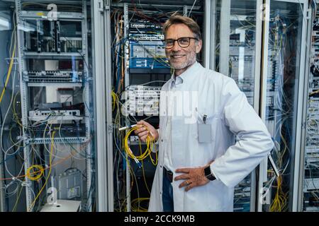 I professionisti IT di tipo maschile tengono i cavi mentre si trovano in un data center Foto Stock