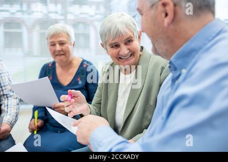 Anziani in gruppo di terapia in casa di pensione scrivere le note su fogli di carta Foto Stock