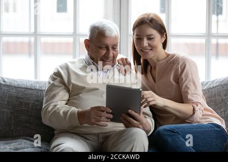 Il vecchio retriee che mostra le foto divertenti sul tablet digitale alla figlia. Foto Stock