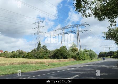 Gruppo di tralicci elettrici, linee ad alta tensione. Cavi sospesi che trasportano l'elettricità alle città. Strada in primo piano. Foto Stock