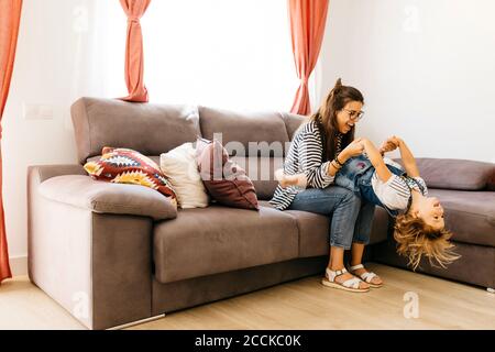 Madre e figlia felici che giocano sul divano a casa Foto Stock