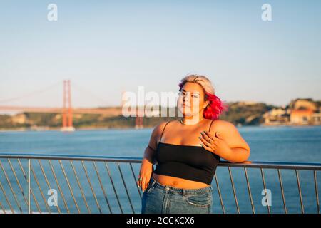 Bella donna appoggiata sulla ringhiera sul lungomare Foto Stock