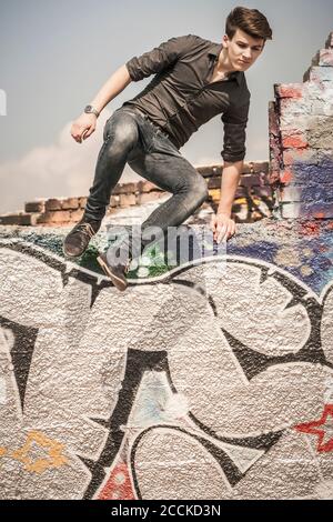 Ragazzo adolescente che salta fuori muro in una vecchia corsa giù area industriale Foto Stock