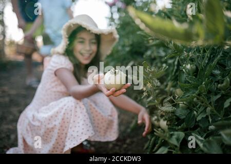Sorridente ragazza che mostra pomodori in orto Foto Stock