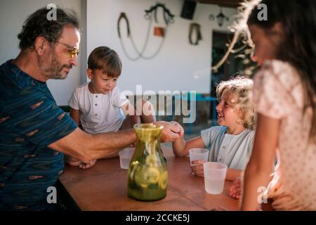 Nipoti e nonno che giocano sul portico Foto Stock