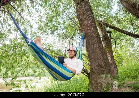 Uomo che si rilassa sull'amaca nella foresta Foto Stock