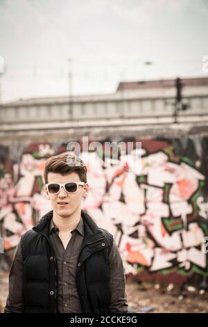 Ritratto di un ragazzo adolescente che indossa occhiali da sole in un vecchio correre giù l'area industriale Foto Stock