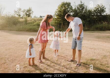 Genitori con due figlie in piedi su un prato Foto Stock