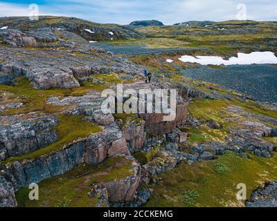 Russia, Murmansk Oblast, Teriberka, veduta aerea di due uomini in piedi sulla costa rocciosa Foto Stock