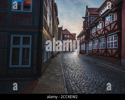 Germania, Schleswig-Holstein, Lauenburg, Brick case lungo vuota strada ciottolata città al crepuscolo Foto Stock