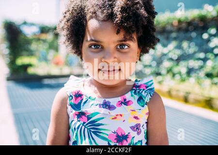 Primo piano ritratto di cute baby girl con capelli ricci in piedi all'aperto Foto Stock
