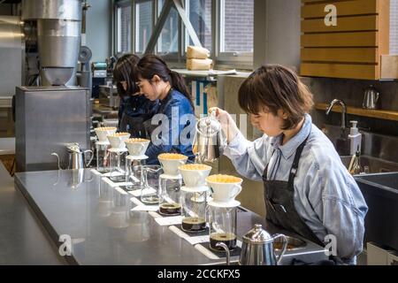 Tokyo, Giappone - baristi che fanno gocciolare la mano, o versare sopra il caffè in bottiglia blu caffè Kiyosumi-Shirakawa Roaissy and Cafe. Foto Stock