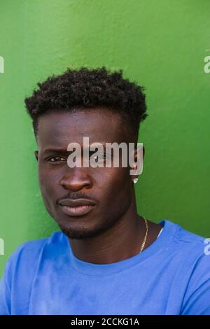 Primo piano di un giovane africano contro il muro verde Foto Stock