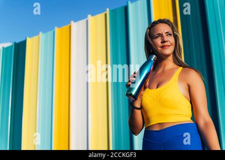 Jogger femmina con pallone da vuoto davanti alla parete colorata Foto Stock