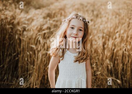 Carino ragazza bionda in piedi in campo di grano Foto Stock