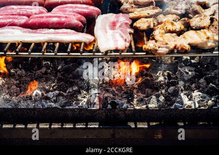 Primo piano di carne e calici sulla griglia barbecue in cortile Foto Stock