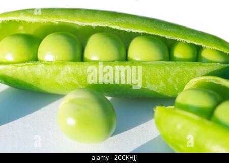 Macro shot di piselli verdi freschi con fagioli isolati su sfondo bianco. Piselli dolci in primo piano isolati su bianco con percorso di ritaglio. Pea pod aperti wi Foto Stock