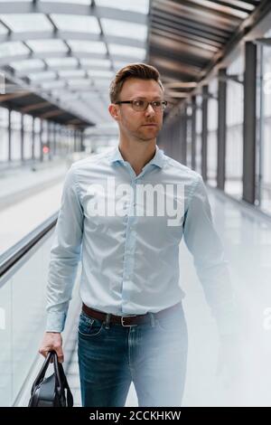 Uomo d'affari con borsa che guarda via mentre si cammina in città Foto Stock